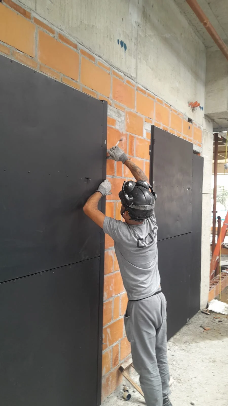Instalador da GOD fixando portas de proteção em vão de elevador na obra